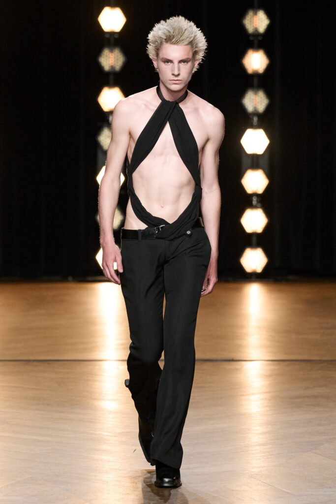 A fitted black sleeveless top with an asymmetric design paired with fitted black pants.