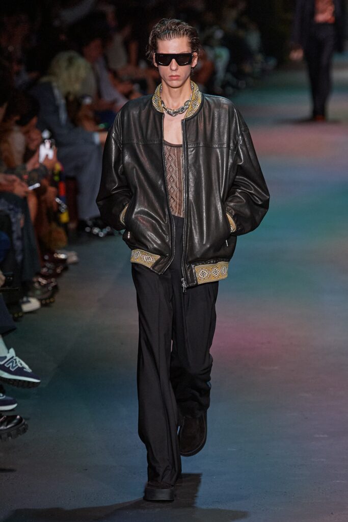 A relaxed black leather jacket with long sleeves and zippered details, paired with matching pants.