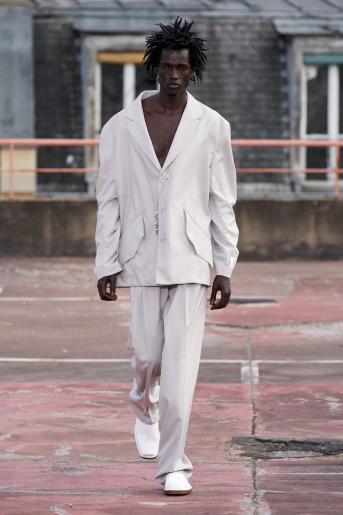 A relaxed white cotton suit with long sleeves and a collared design, featuring button details.