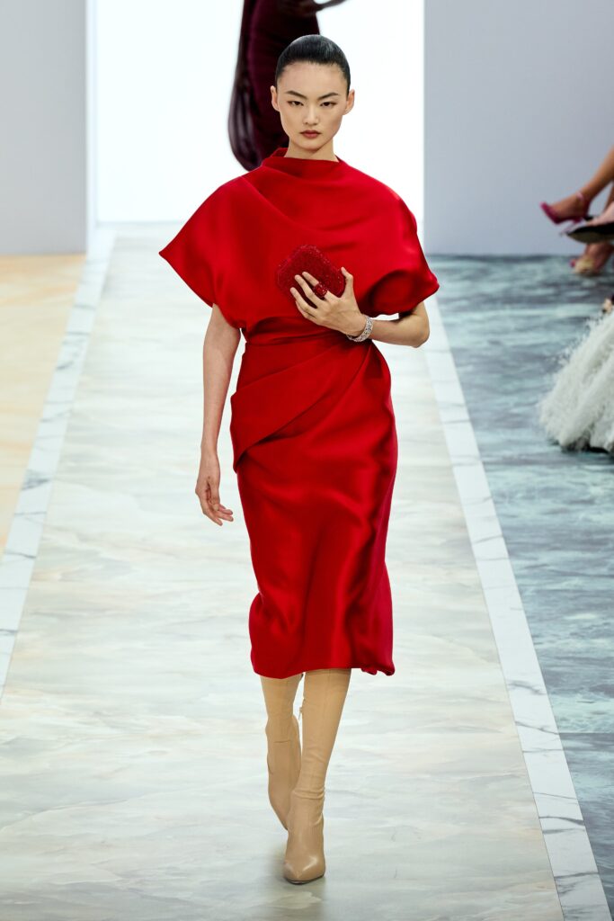 A fitted red silk dress with a high neckline and asymmetric design detail.