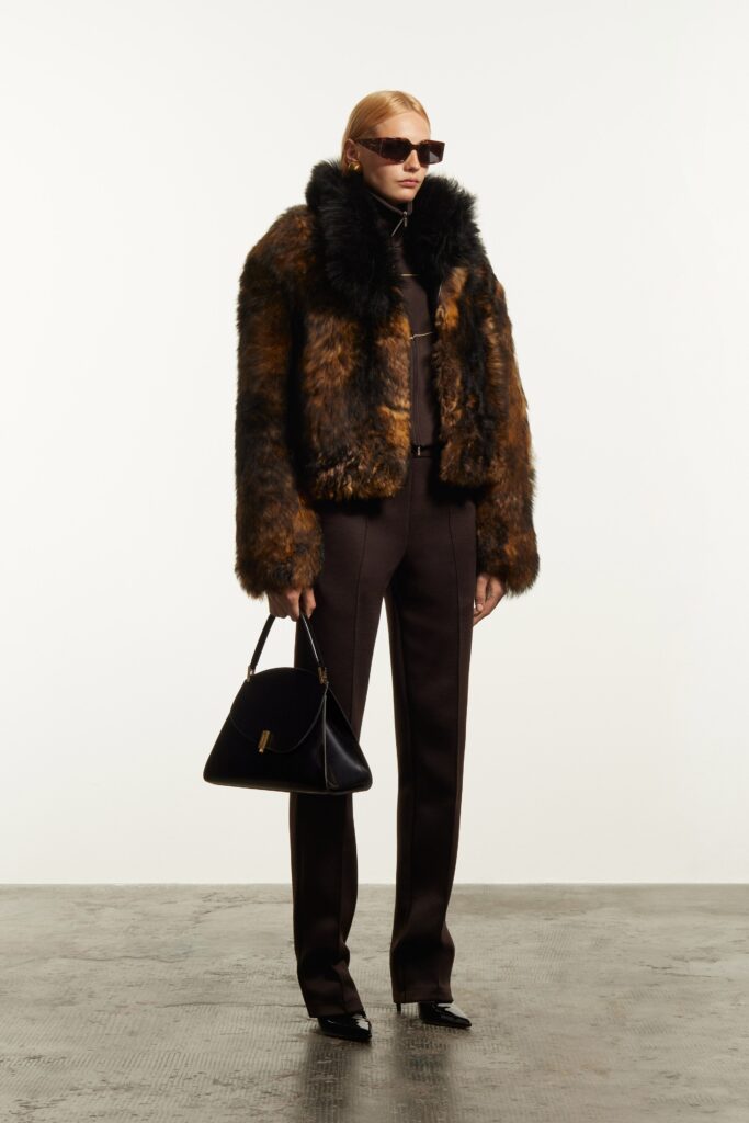 A fitted brown fur jacket with long sleeves and collared design paired with tailored pants.