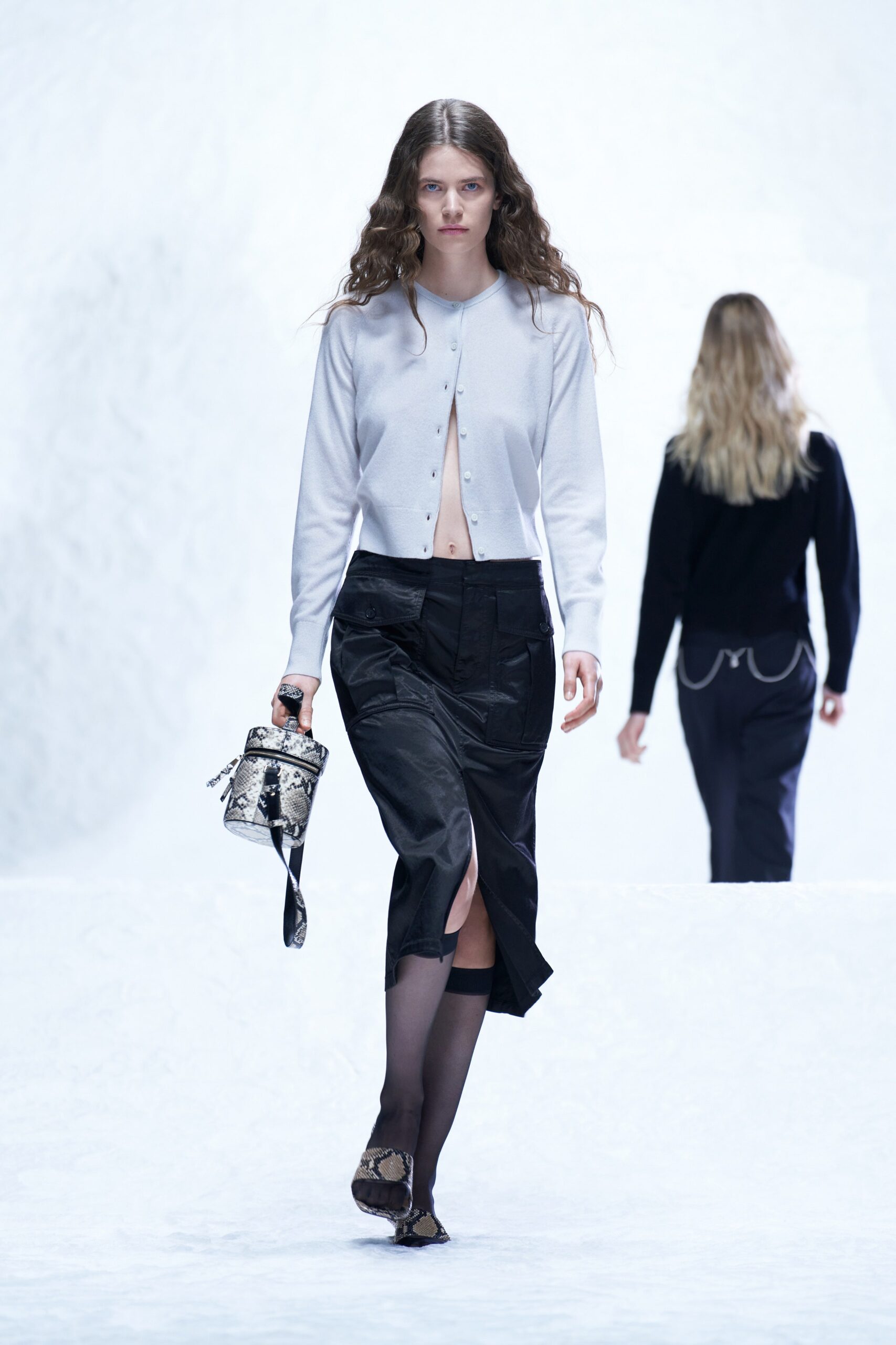 A fitted gray long-sleeve top with a collared design paired with a black silk skirt featuring a slit.