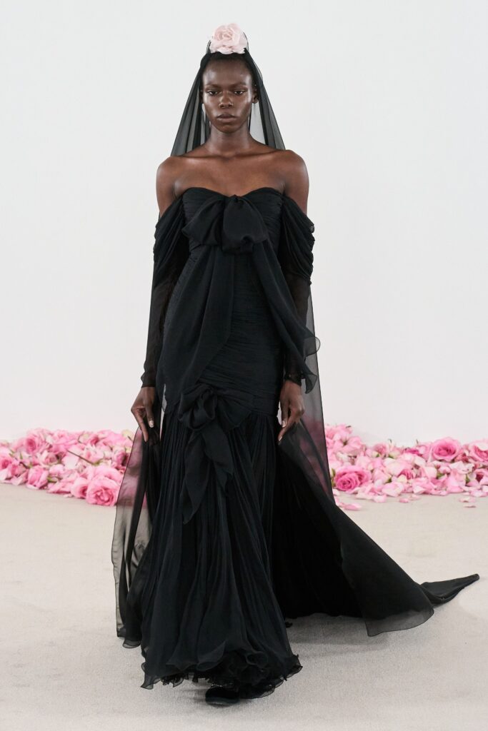 A fitted black silk gown with an off-shoulder design and draped detailing.