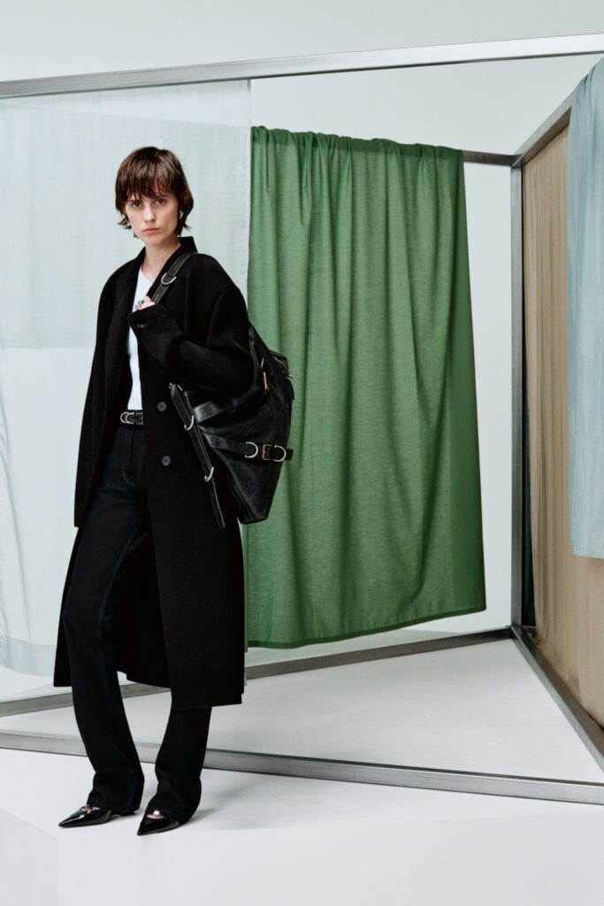 A fitted black wool coat with a collared neckline paired with straight-leg pants.