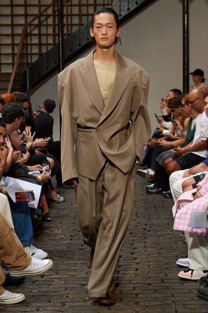 An oversized beige suit with long sleeves and a collared design, featuring buttoned details.