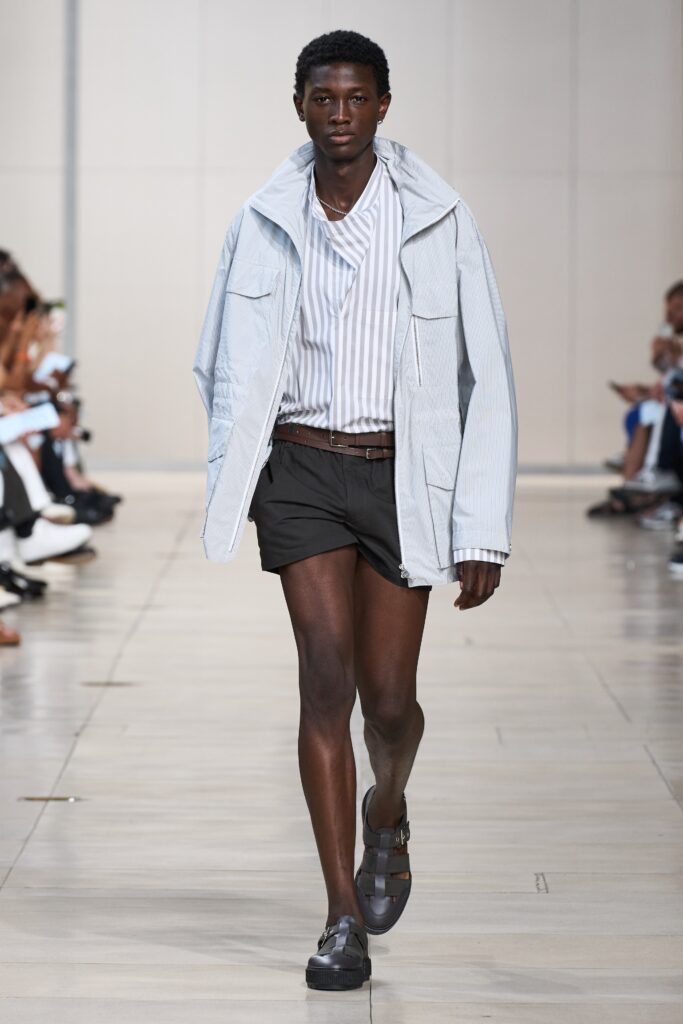 A relaxed blue striped jacket paired with black shorts for a casual runway look.