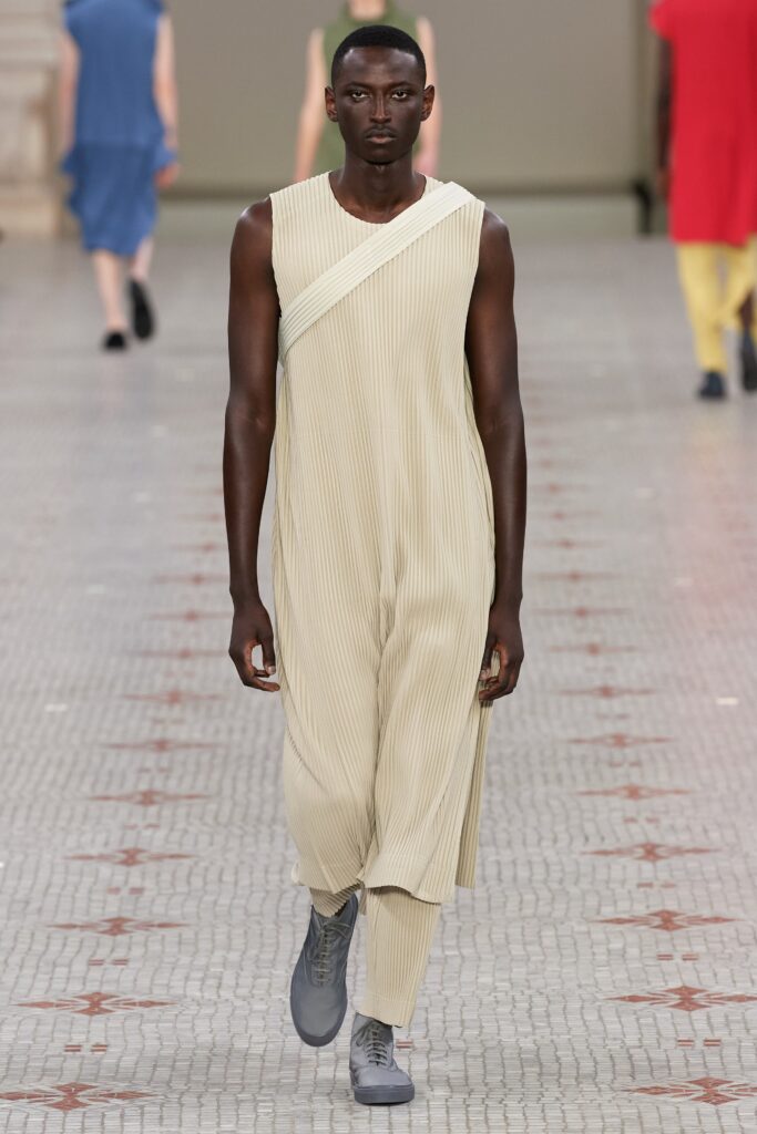 A relaxed beige sleeveless jumpsuit with a high neckline and pleated design.