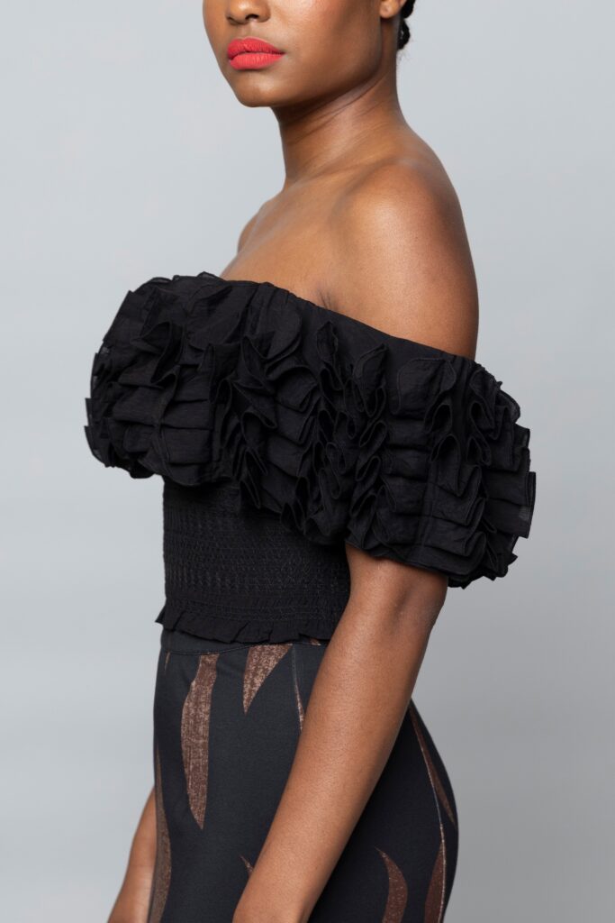 A fitted black cotton off-shoulder top with ruffled detailing.