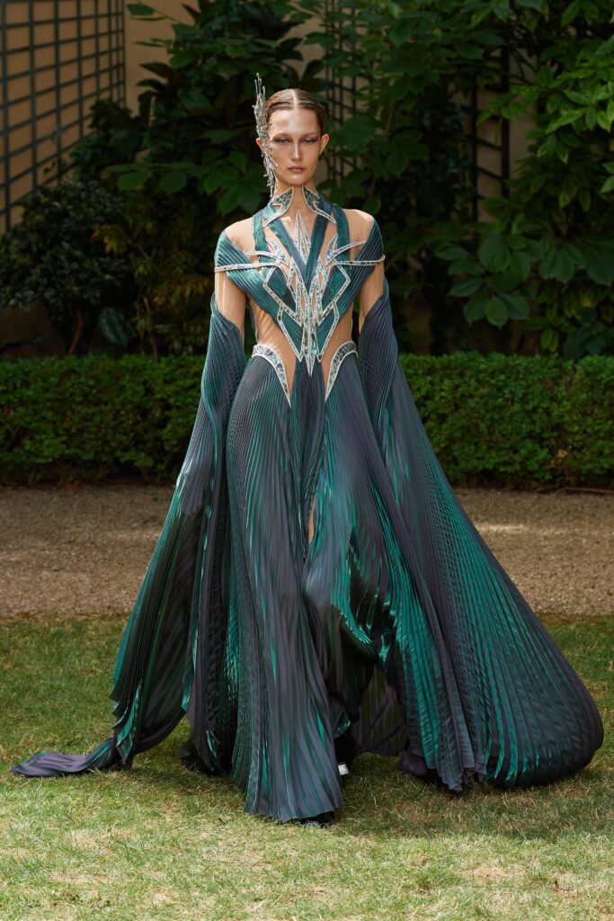A fitted green silk dress with a V-neckline and pleated, draped design details.