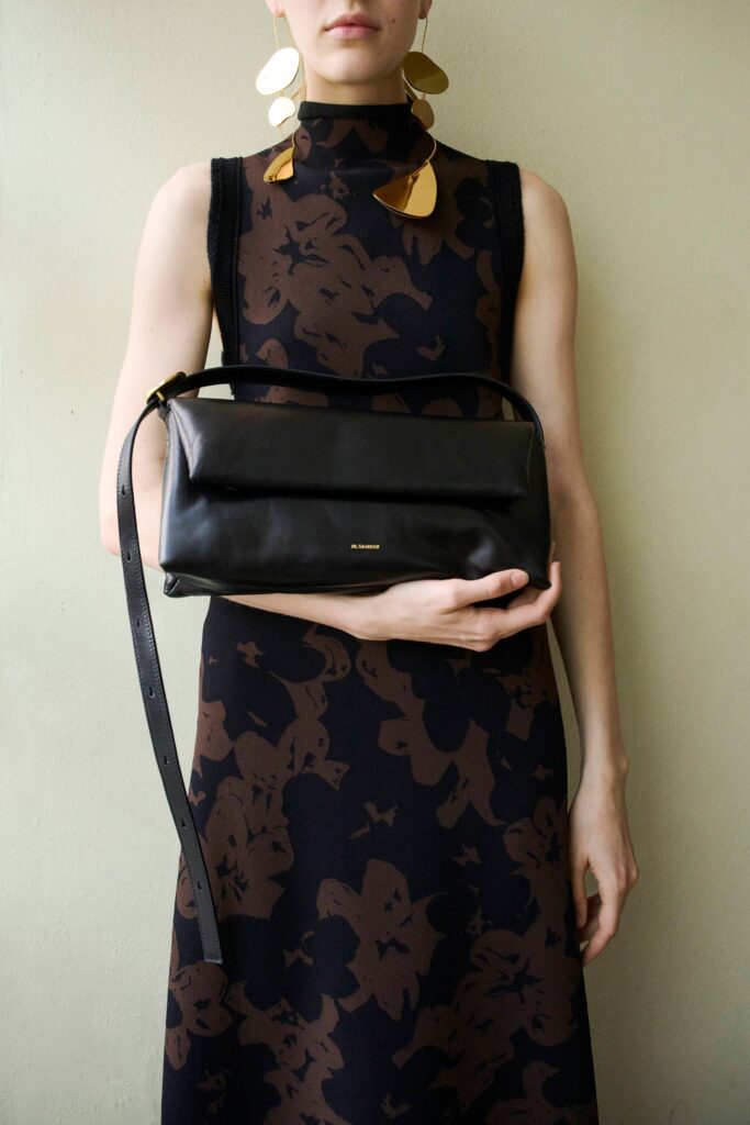 A fitted black sleeveless dress with a high neckline featuring a floral design.