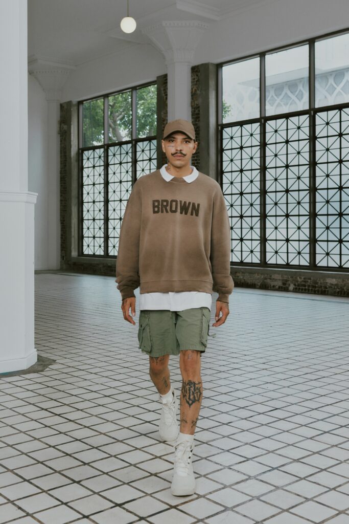 A relaxed brown sweater with a printed design paired with green shorts.
