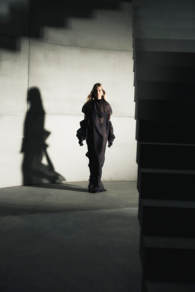 A relaxed black silk dress with long sleeves and an asymmetric design.