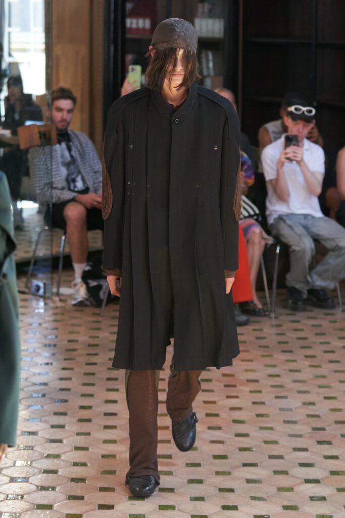 A relaxed black wool coat with long sleeves and an asymmetric design paired with matching pants.