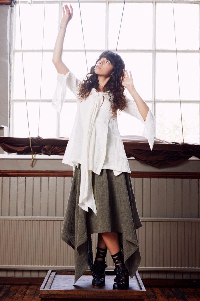 A relaxed white long-sleeve top paired with an asymmetric gray layered skirt.