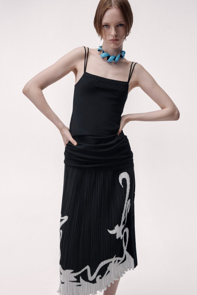A fitted black sleeveless dress with a V-neckline and pleated design detail.