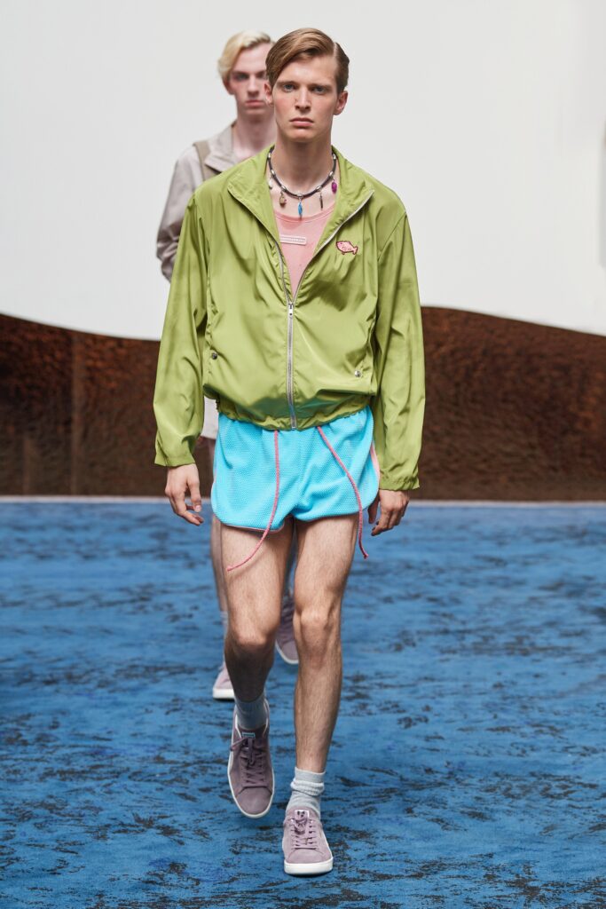 A relaxed fit green jacket with a collared neckline paired with blue shorts.