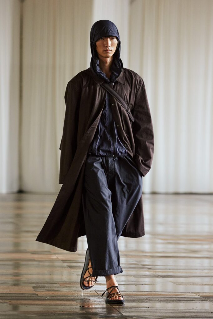 A relaxed brown hooded coat paired with black pants, featuring a buttoned design.