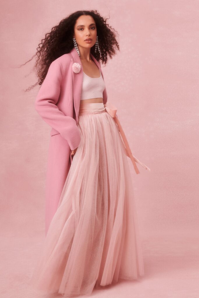 A fitted pink tulle skirt layered with a long-sleeve coat featuring a high-neck design.