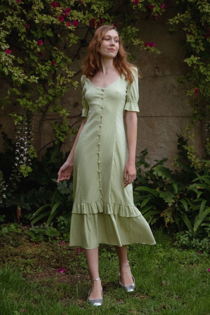 A relaxed green cotton dress with short sleeves, a V-neckline, and a tiered design.