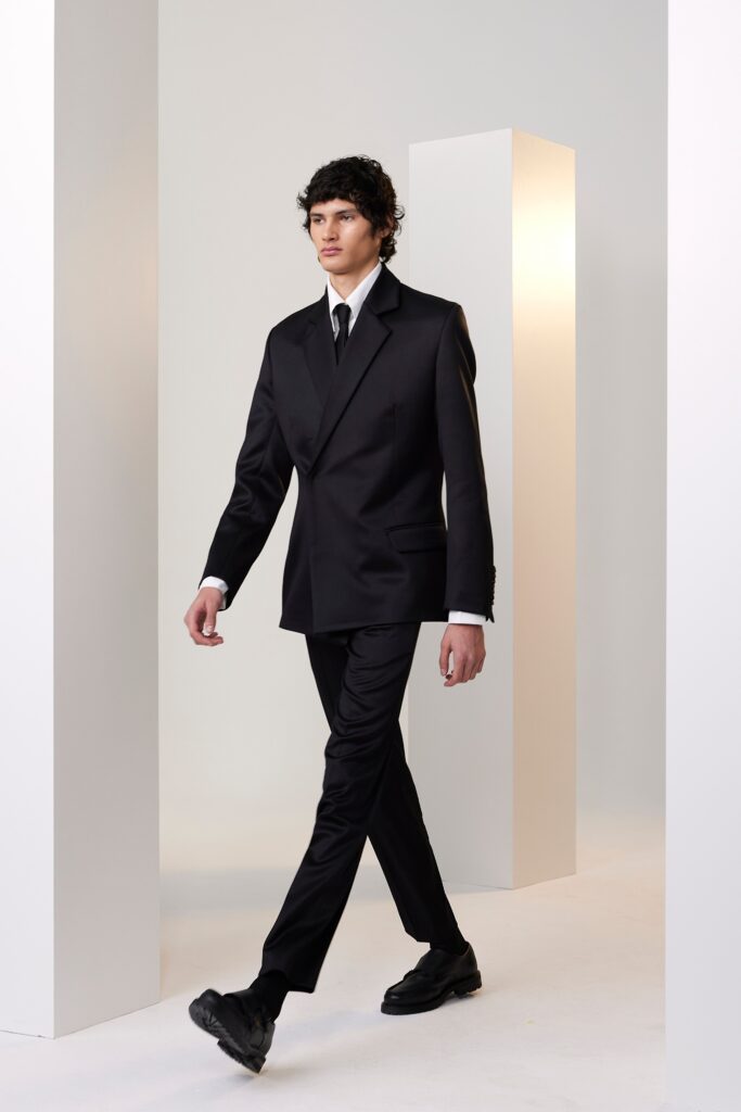 A tailored black suit with long sleeves and a collared shirt, featuring buttoned details.