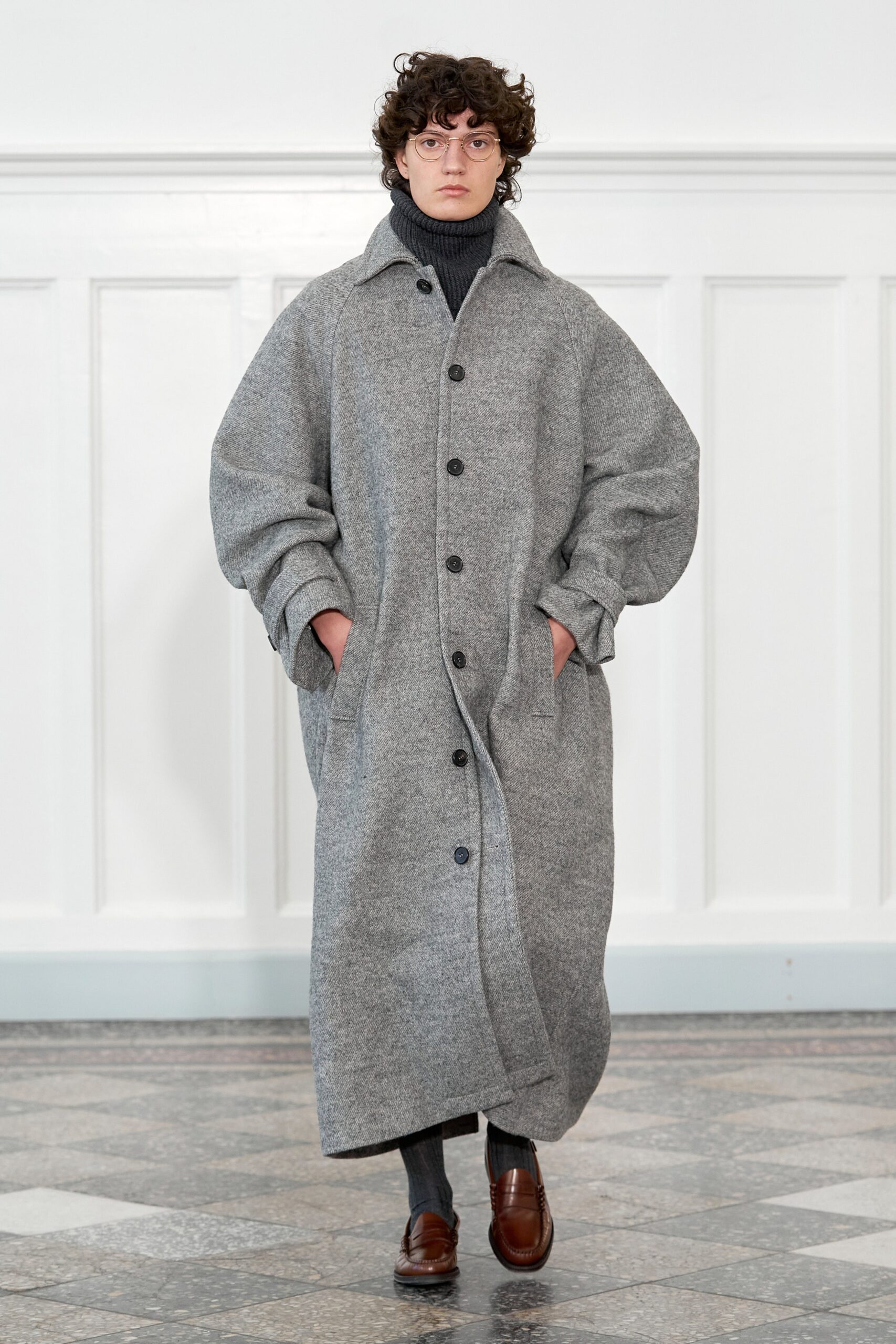 An oversized gray wool coat with long sleeves and a collared design, featuring button closures.