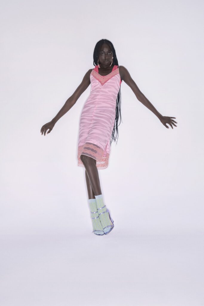 A fitted pink silk dress with a V-neckline and asymmetric design.