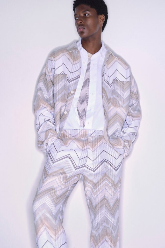 A relaxed white long-sleeve collared shirt paired with striped beige pants.
