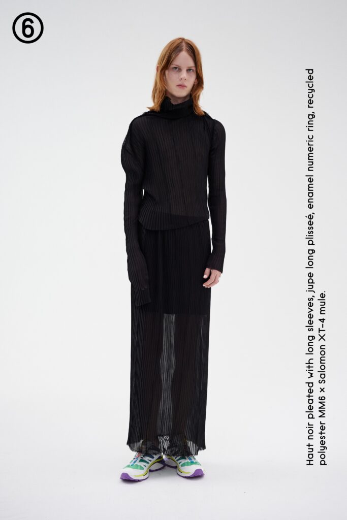A fitted black pleated dress with long sleeves and a high neckline.
