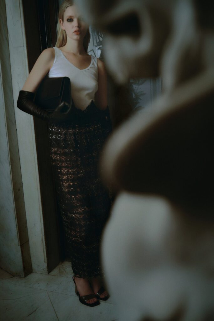 A fitted black lace skirt paired with a sleeveless white top, showcasing a layered and sheer design.