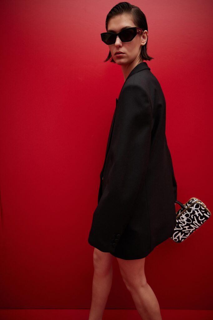 This oversized black blazer dress features a striking asymmetric silhouette that plays with traditional tailoring. The long sleeves and collared neckline add a structured element, while the relaxed fit offers a contemporary twist on classic styles.