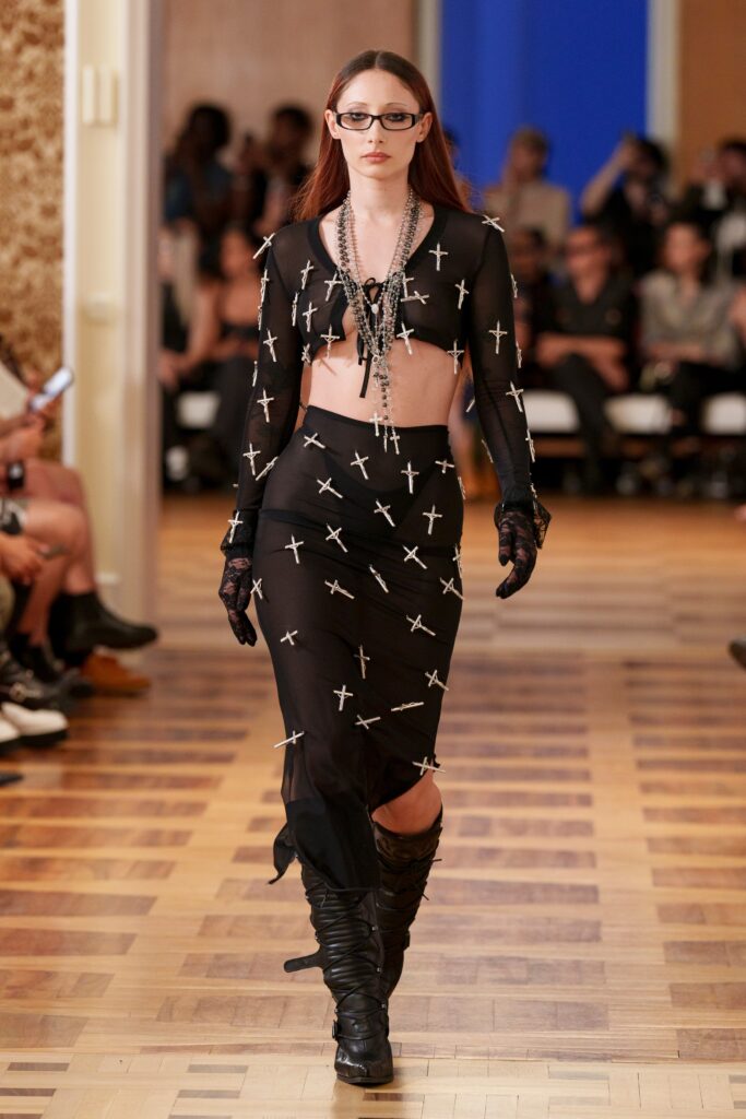A fitted black sheer sleeveless dress adorned with cross motifs and a stylish silhouette.