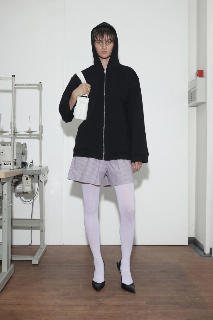 A relaxed black hoodie paired with striped shorts, creating a casual yet stylish look.