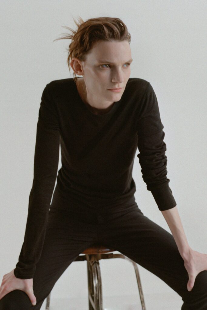 A fitted black cotton long-sleeve top paired with straight-leg black pants.