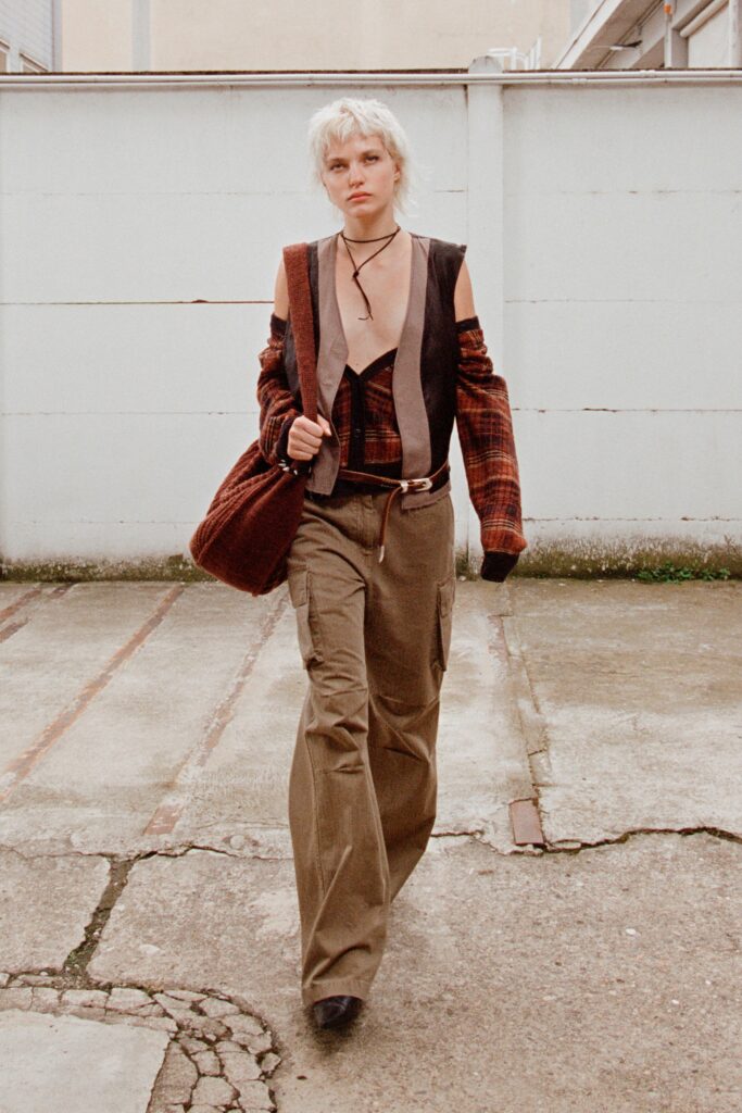 A relaxed brown jacket with an asymmetric design paired with loose-fitting pants.