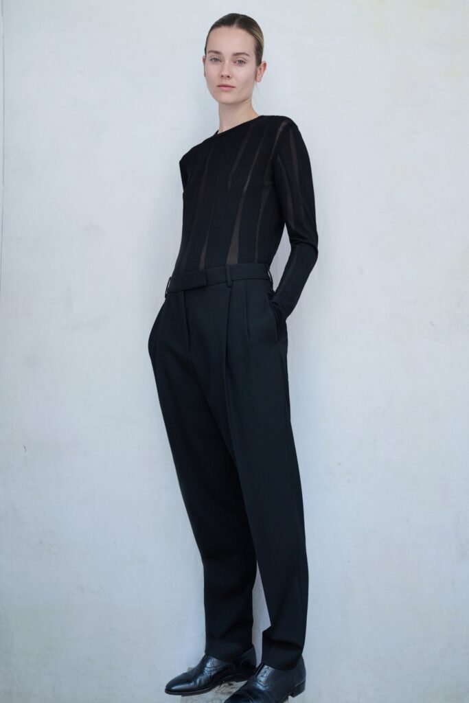 A relaxed black long-sleeve top with stripes paired with black pants.