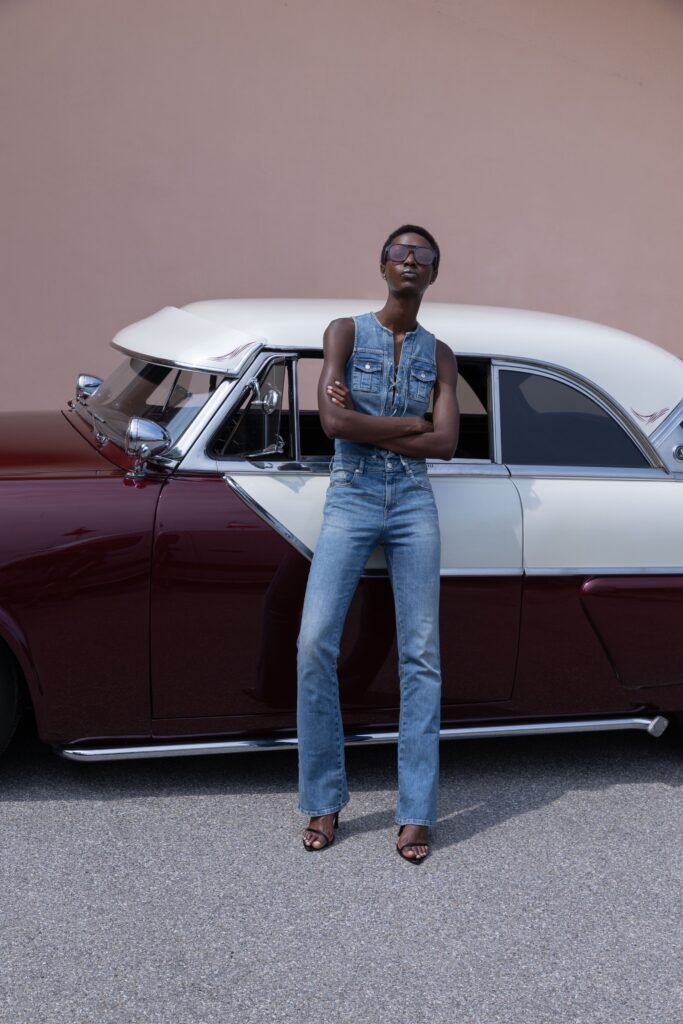 A fitted blue denim jumpsuit with a sleeveless design and straight-leg silhouette.