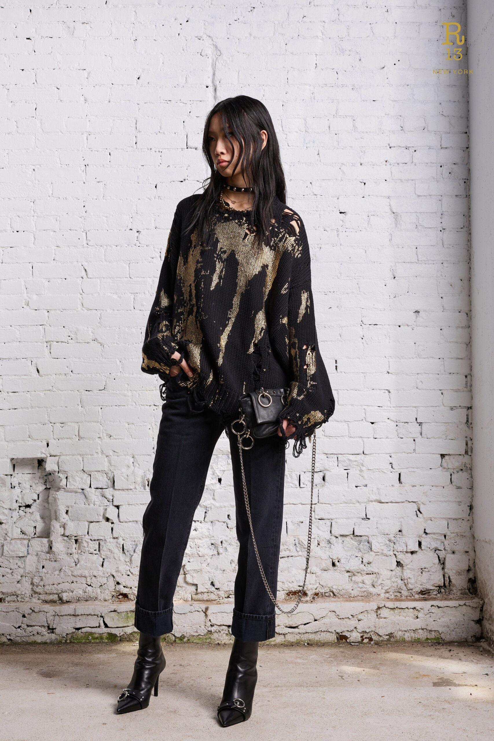 A relaxed black and gold printed long-sleeve top paired with black pants.