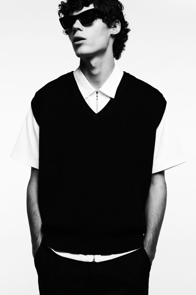 A relaxed black sweater layered over a white short-sleeve shirt with a V-neckline.