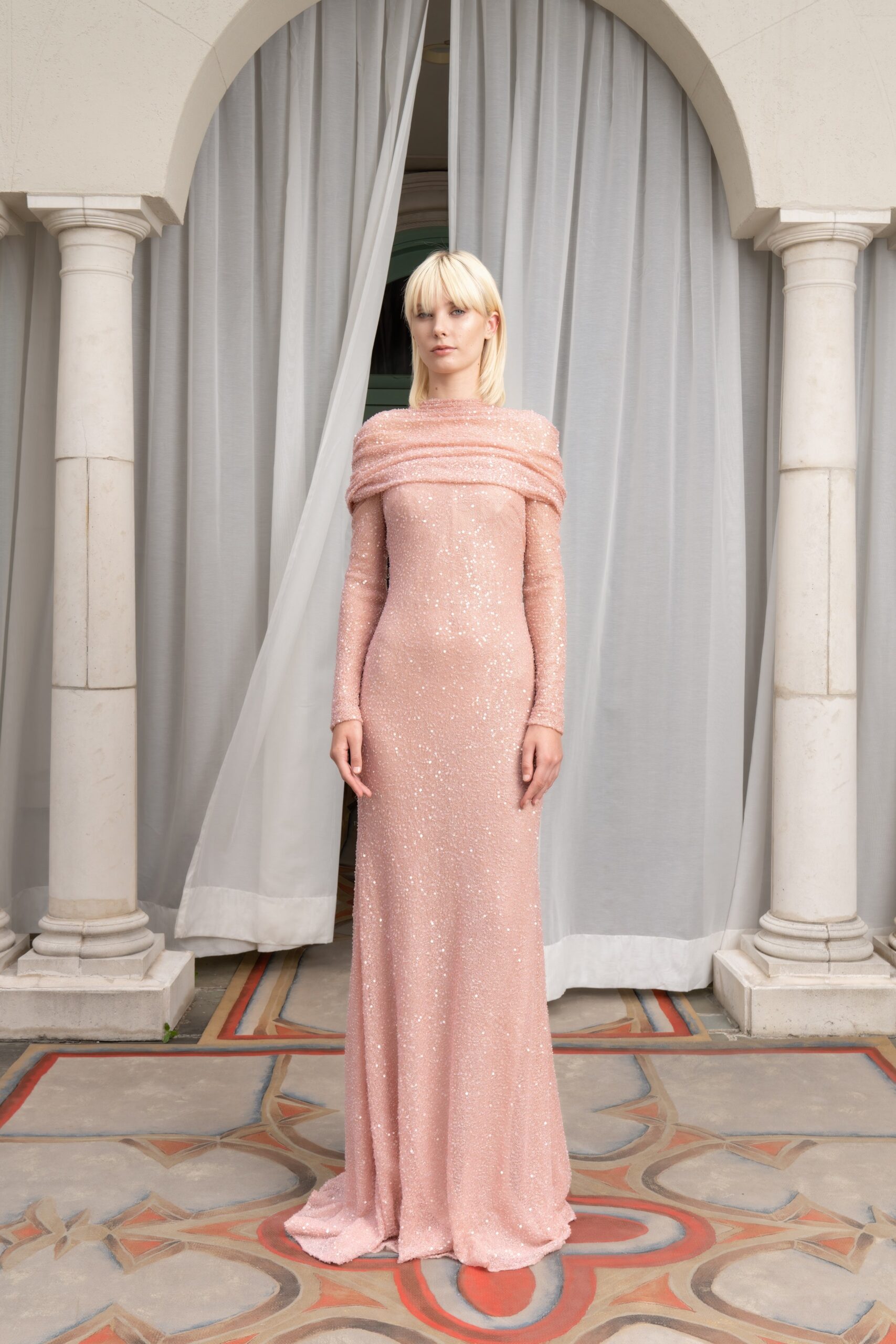 A fitted pink silk gown with long sleeves and a sequined design.