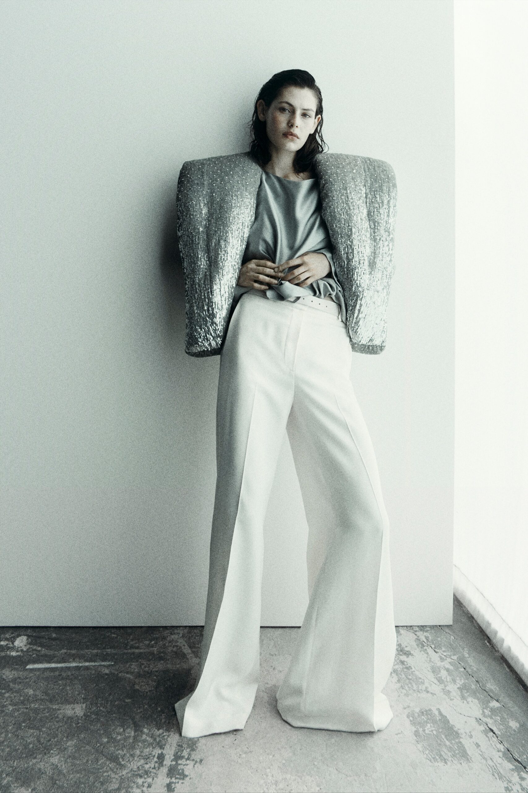 A fitted outfit featuring wide-leg white pants and a long-sleeve silver sequined jacket.