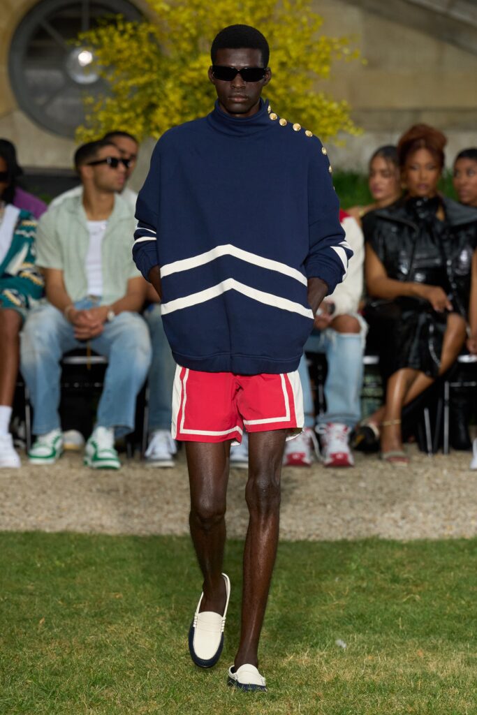 A relaxed blue striped sweater with long sleeves paired with red shorts.