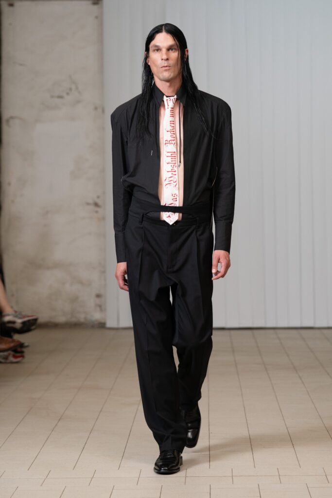 A black cotton long-sleeve shirt paired with tailored black pants for a sleek look.