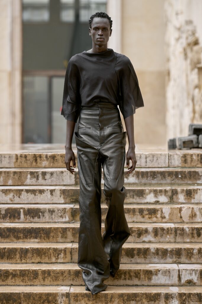 A fitted black leather top with short sleeves paired with high-waisted wide-leg pants.