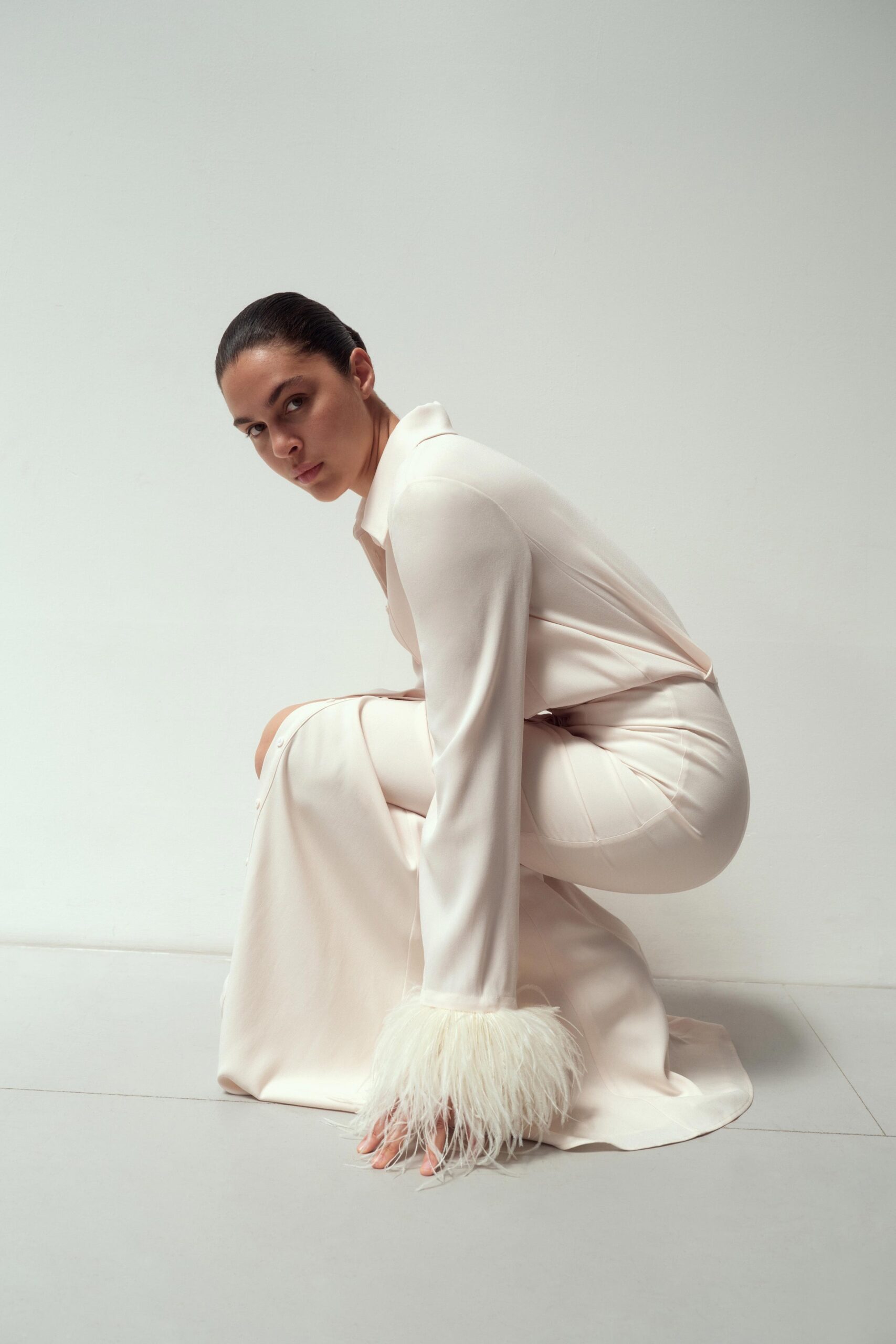 A fitted white silk dress with long sleeves, a collared neckline, and tiered design details.