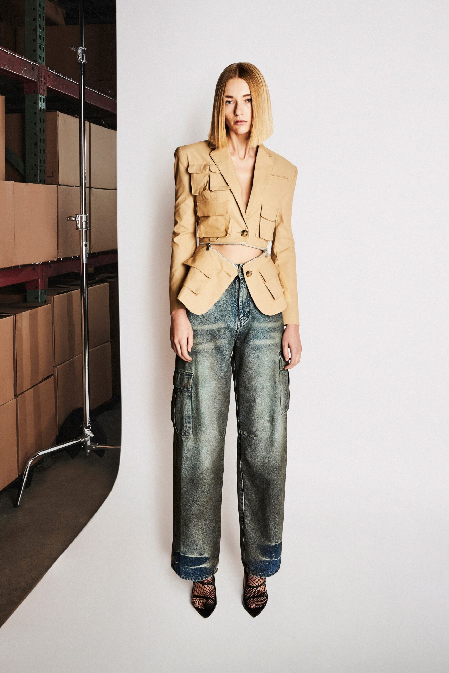 A relaxed beige jacket with long sleeves and a collared design paired with wide-leg blue pants.