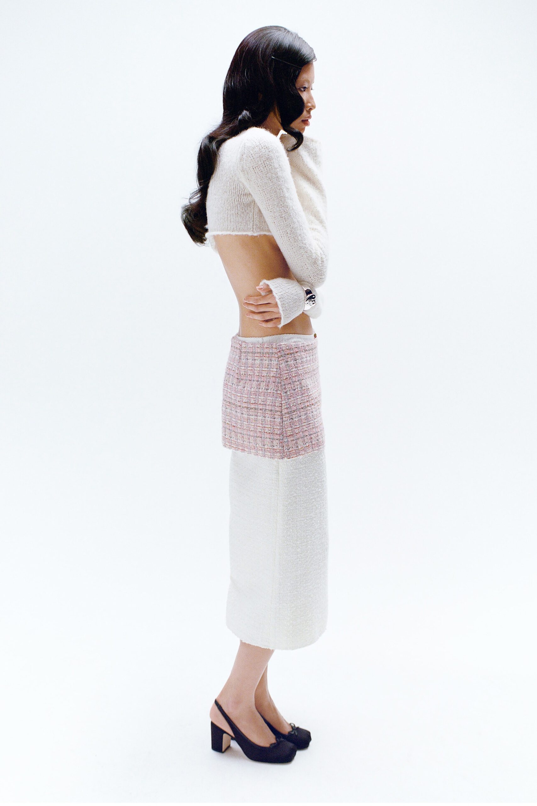 A fitted white sleeveless top with a high-neck paired with a layered pink skirt.