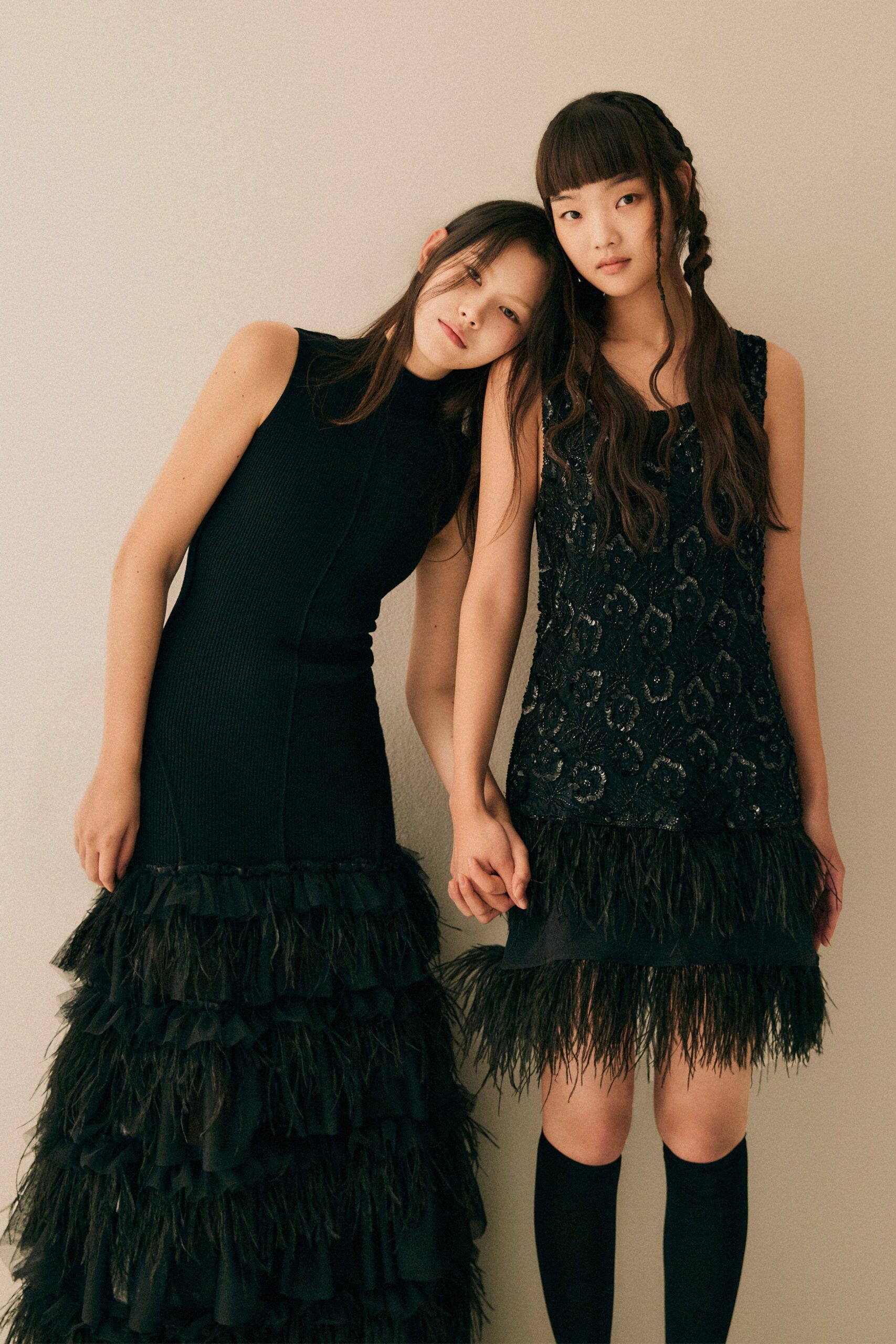 A fitted black sleeveless dress with a high neck and tiered design details.