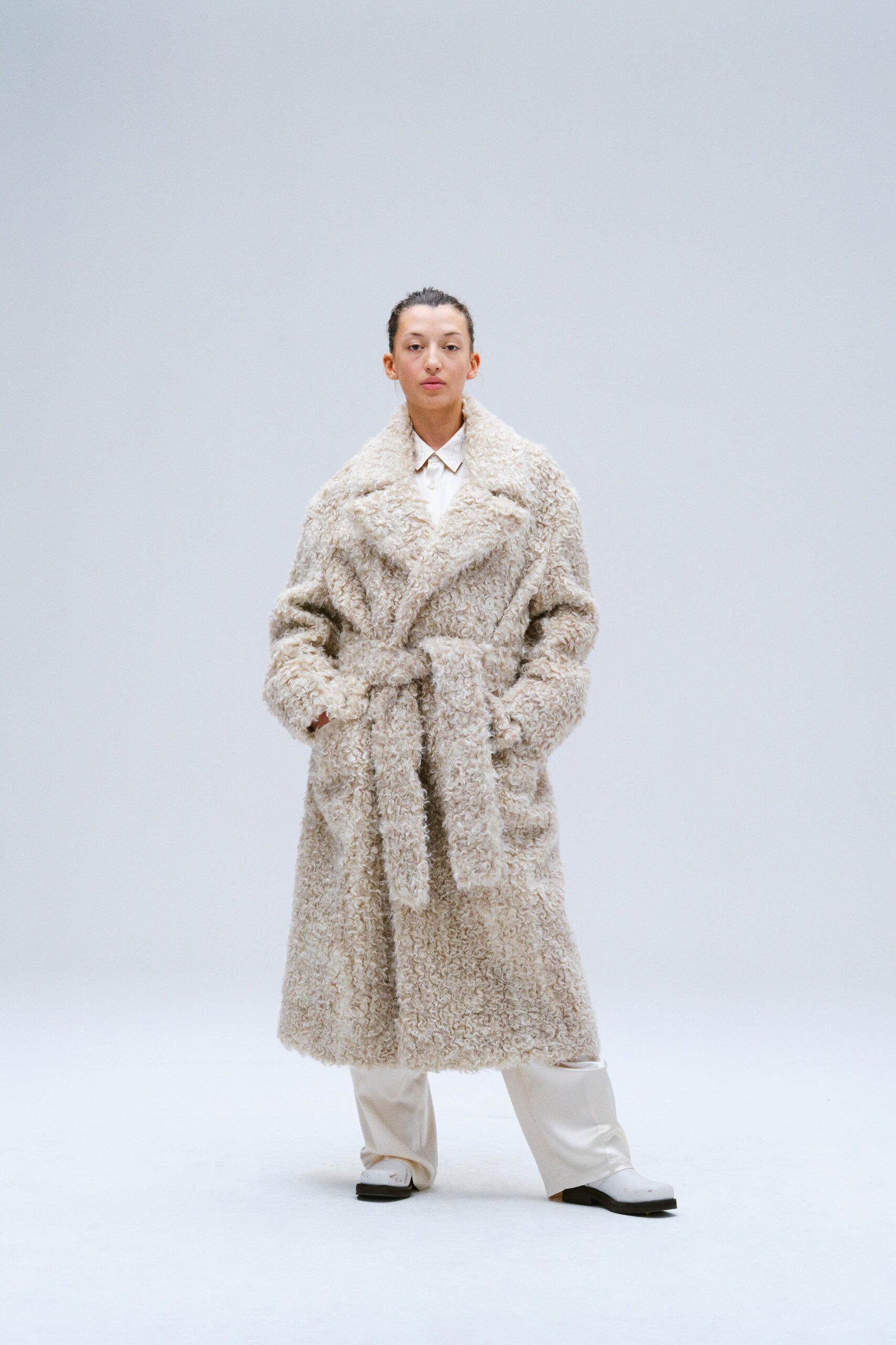 A relaxed beige fur coat with long sleeves and a belted design.