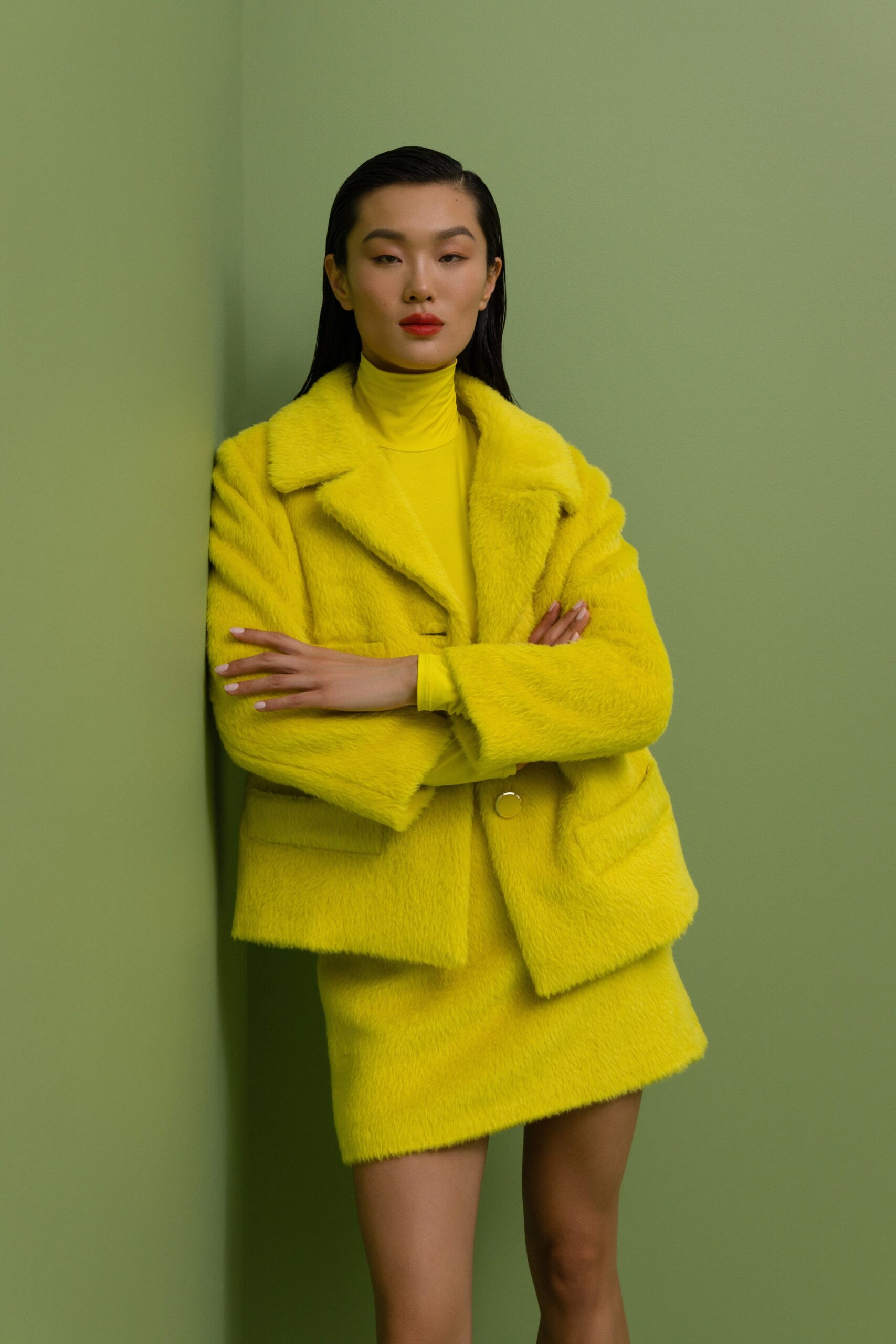 A fitted yellow faux-fur jacket with a collared neckline paired with a matching skirt.
