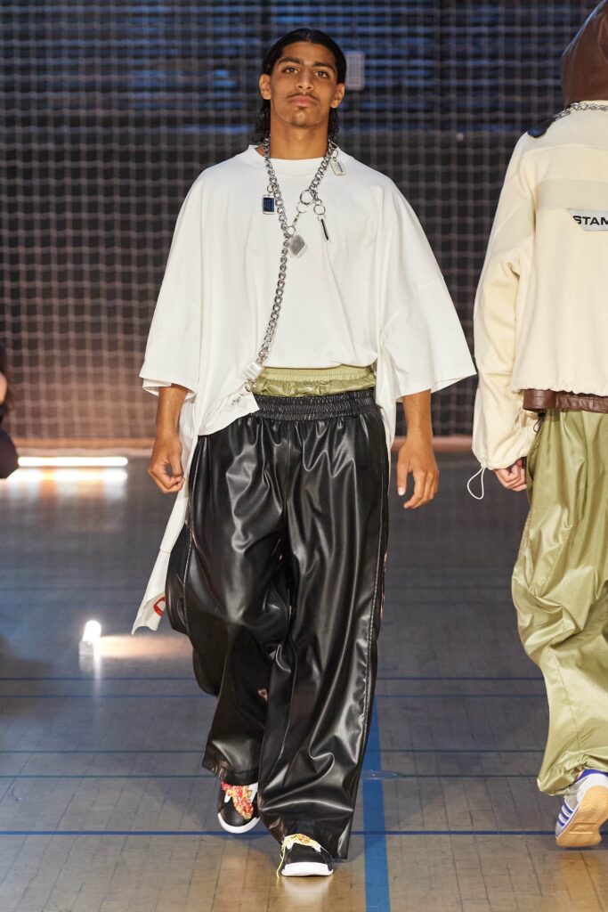 A relaxed white short-sleeve top with layered black pants for a contemporary look.